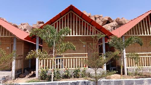 a house with a fence and some trees and rocks at Osho's Organic Resort Hampi in Hampi