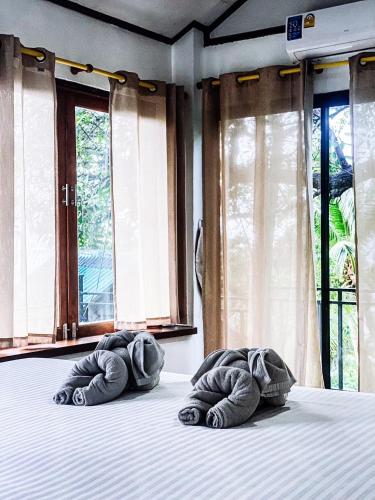 two rolled up towels on a bed in front of windows at P.D. Beach Resort in Ko Tao