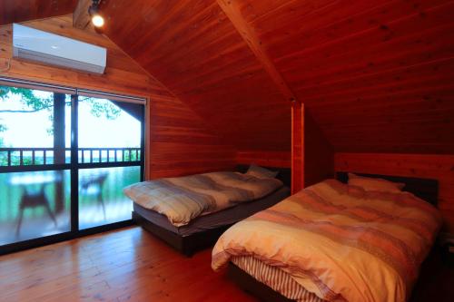 a bedroom with two beds in a wooden cabin at Yuushin in Mifune