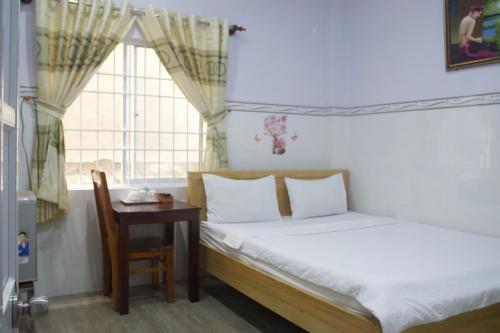 a bedroom with a bed and a table and a window at Duong Hieu Guesthouse in Phu Quoc