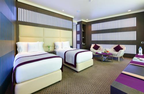 een hotelkamer met 2 bedden en een bank bij The Torch Doha in Doha