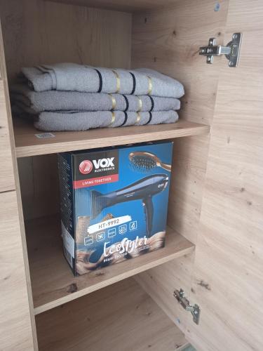 a shelf with a box and towels in a drawer at MAL Apartman in Soko Banja