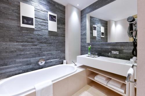 uma casa de banho com uma banheira branca e uma parede preta em The Torch Doha em Doha