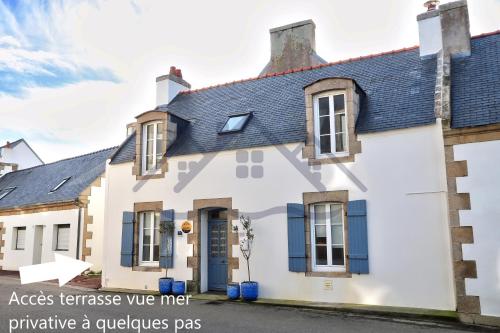 une maison blanche avec des fenêtres bleues et un toit dans l'établissement LocaLise - M4 - La maison de la pointe de Lechiagat - Accès à deux pas d'une terrasse vue mer privative - Wifi inclus - Draps inclus - Animaux bienvenus, à Tréffiagat