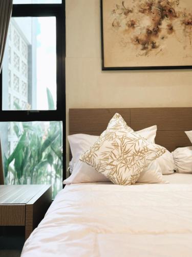 uma cama com lençóis brancos e almofadas num quarto em Apartment Nawasena em Sanur