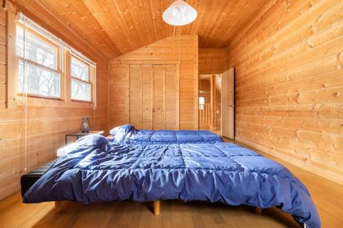 コテージLog في ناسو: غرفة نوم بسرير ازرق في كابينة خشبية