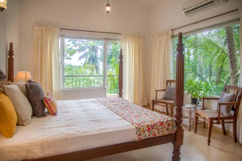 1 dormitorio con cama y ventana grande en Frangipani by Hireavilla - 4BR with Private Pool in Nerul, en Nerul