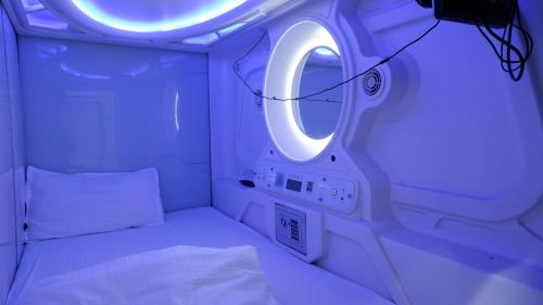 mały pokój z łóżkiem i okrągłym lustrem w obiekcie Astropods w Bombaju