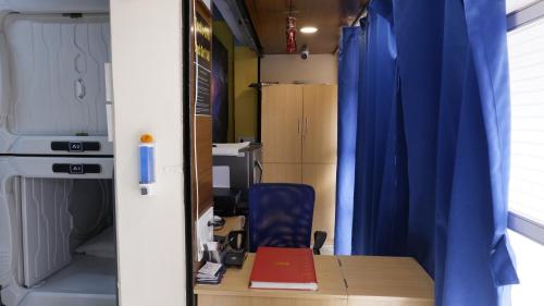 Habitación con escritorio y cortina azul en Astropods en Bombay