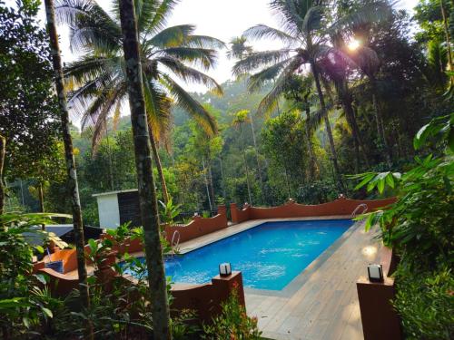 uma piscina num resort com palmeiras em Beverly hills holiday homes em Vythiri