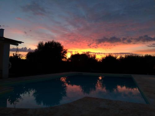 a sunset over a swimming pool at sunset at Trullo Felice in Ostuni