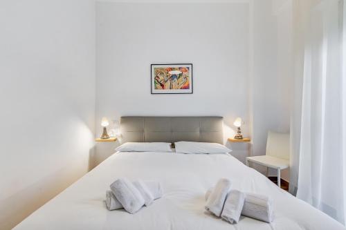 a white bedroom with a large white bed with two pillows at Ciampino Luxe -15min Termini, Airport and Train Station - in Ciampino