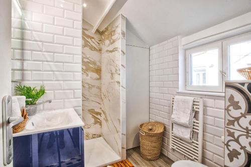 een witte badkamer met een wastafel en een raam bij La Maison de Pêcheur de Ginette in Cabourg