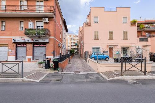an empty city street with buildings and a blue car at Ciampino Luxe -15min Termini, Airport and Train Station - in Ciampino