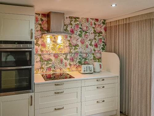 a kitchen with white cabinets and a floral wallpaper at The Venetian in Horning