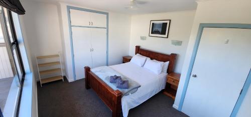 Schlafzimmer mit einem Bett mit weißer Bettwäsche und Kissen in der Unterkunft Spa, Stay & Holiday in Rotorua