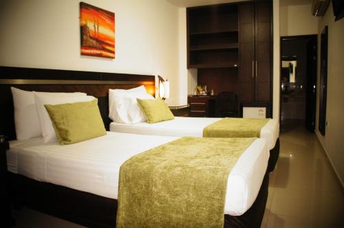 a hotel room with two beds and a table at Hotel San José Plaza in Bucaramanga