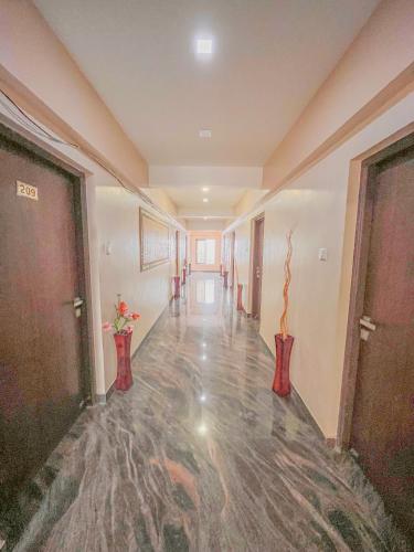 an empty hallway in a building with doors and vases at StayGuru Park View Residency in Bhuj