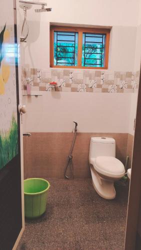 a bathroom with a toilet and a green bucket at UPPU HOMESTAY in Mulappilangād