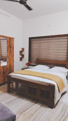 a bedroom with a large bed with a wooden headboard at UPPU HOMESTAY in Mulappilangād