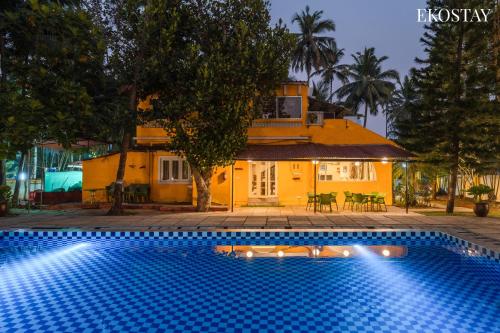 a swimming pool in front of a house at EKOSTAY - Polaris Villa in Majorda