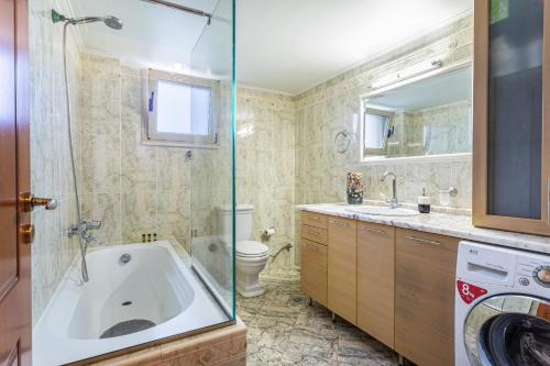 a bathroom with a tub and a toilet and a sink at kallia's lux apt with sea view & cool jacuzzi in Plataniás