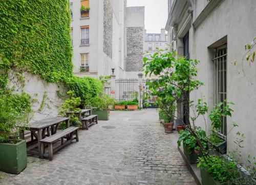 une cour avec des bancs et des plantes dans un bâtiment dans l'établissement Charmant Studio 2 pers à Paris, à Paris