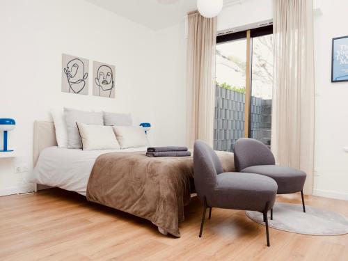 a white bedroom with a bed and a chair at Le 6 - Appartement douillet strasbourgeois avec terrasse in Strasbourg