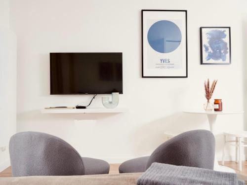 a living room with two chairs and a flat screen tv at Le 6 - Appartement douillet strasbourgeois avec terrasse in Strasbourg
