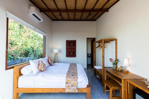 a bedroom with a bed and a desk and a window at Nalika Beach Resort & Restaurant - Adults Only in Umeanyar