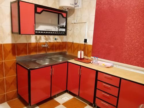 a kitchen with red cabinets and a sink at دار السلام للشقق المخدومة الجوف دومة الجندل in Dawmat al Jandal