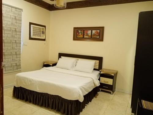 a bedroom with a large bed with white sheets and pillows at دار السلام للشقق المخدومة الجوف دومة الجندل in Dawmat al Jandal