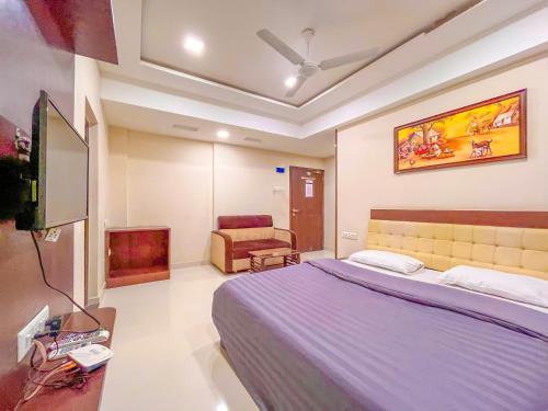 a bedroom with a bed and a tv and a couch at Park View Residency in Bhuj