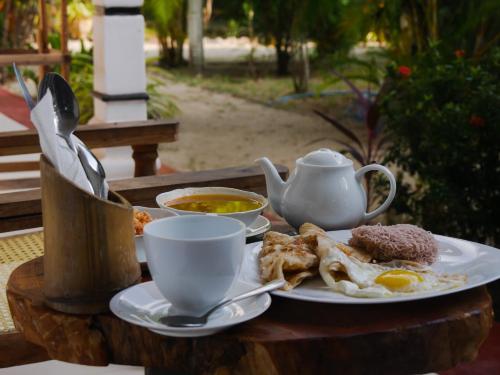 una mesa con un plato de comida y una taza de sopa en Ubay Guest House, en Trincomalee