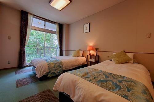 two beds in a room with a window at Guestroom Garden Azumino in Azumino