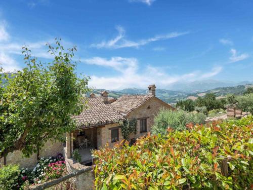 uma antiga casa de pedra com um jardim e montanhas ao fundo em Gorgeous Apartment with Pool near Sibillini Mountains em Monte San Martino