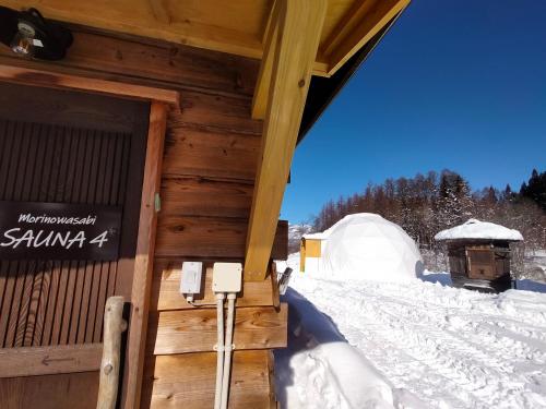 a cabin in the snow with a sign on the door at 白馬森のわさび農園オートキャンプ場 in Hakuba