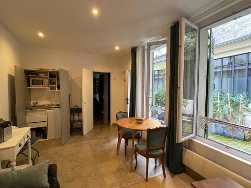 - une cuisine et une salle à manger avec une table et des fenêtres dans l'établissement Charmant et tranquille plein centre de Paris!, à Paris
