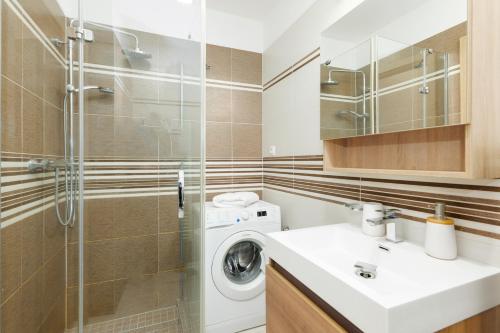a bathroom with a washing machine and a glass shower at HomeAwayHome by the River in České Budějovice