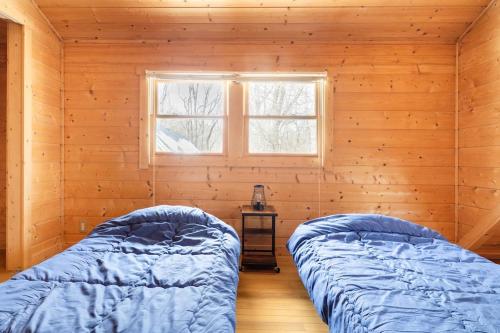 two beds in a log cabin with a window at 森の中の大型ログハウス最大16名可ペット同伴OkコテージLog in Nasu