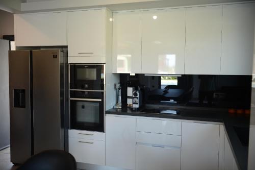 a kitchen with white cabinets and a refrigerator at Luxury Villa Plaka Litochorou with Pool in Plaka Litochorou