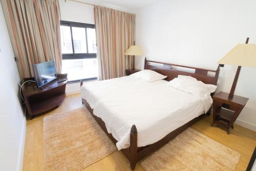 1 dormitorio con 1 cama grande y TV en Saint Lucas Suíte, en Funchal