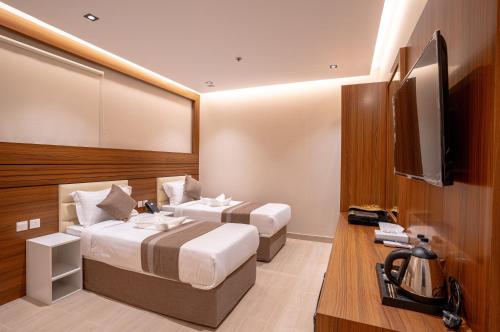 um quarto com 2 camas e uma televisão de ecrã plano em فندق كنانة العزيزية من سما em Meca