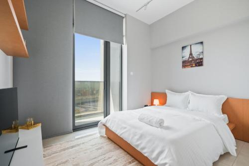 1 dormitorio con cama blanca y ventana grande en Peaceful Studio - Wpool - Gym en Dubái