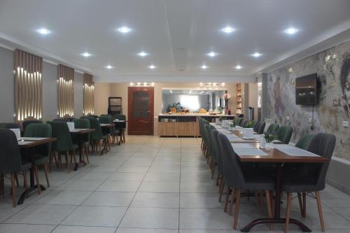 a dining room with tables and chairs and a counter at Altamira Hotel in Karakol