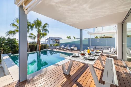 an open deck with a table and chairs next to a swimming pool at Designer Alcanada in Alcudia