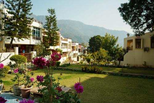 a yard with flowers and buildings and mountains in the background at The Basera in Rishīkesh