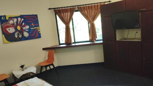 Habitación con TV, silla y ventana. en Smiley Resorts, en Auroville