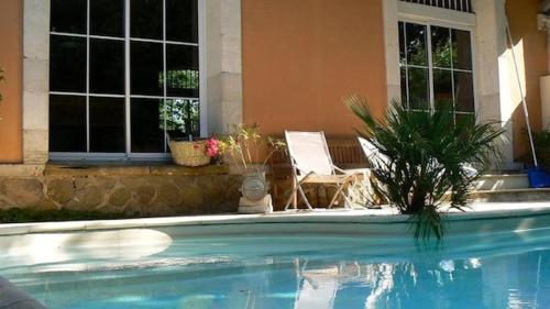 - une piscine en face d'une maison avec une chaise dans l'établissement Grand loft avec piscine privée dans vielle gare, à Pomas