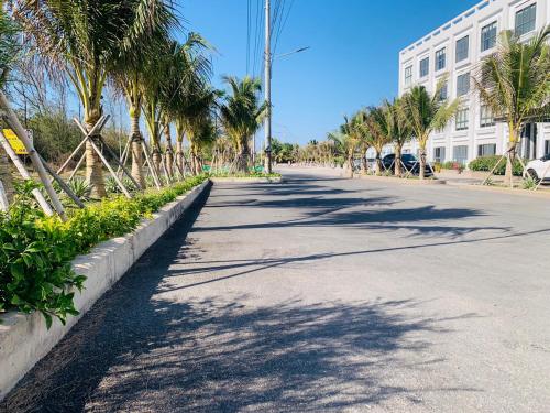 an empty street with palm trees and a building at Bờ Biển Vàng Resort in Ke Ga